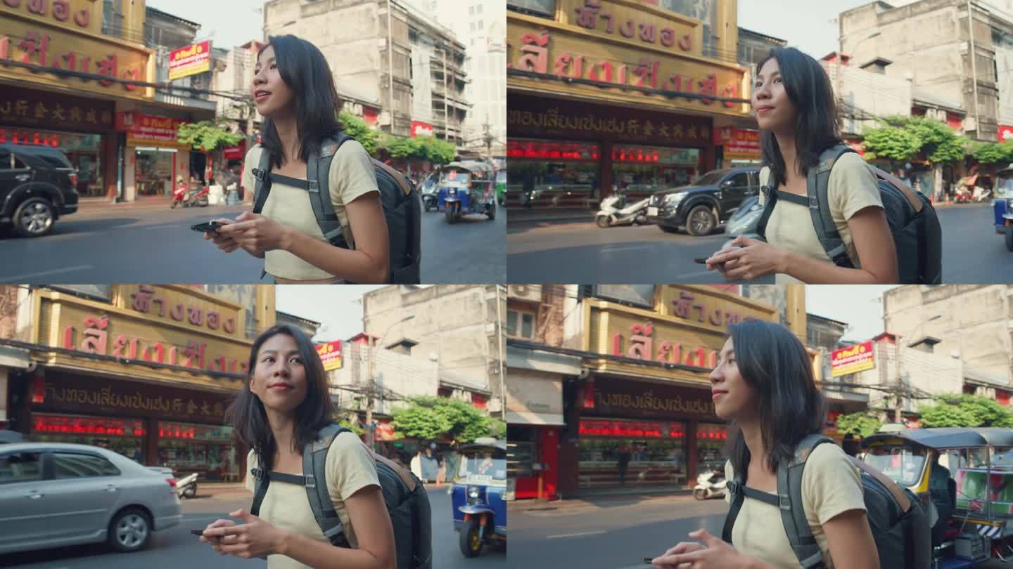 年轻的亚洲女性背包客在城市街道上使用手机。假日度假旅行。