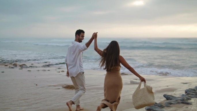 一对情侣一起在海边奔跑的特写。两个人走在水岸边
