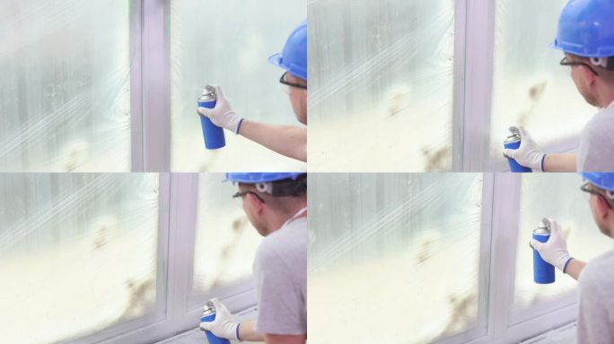 建筑工人正在用罐子里的白色喷漆粉刷窗户