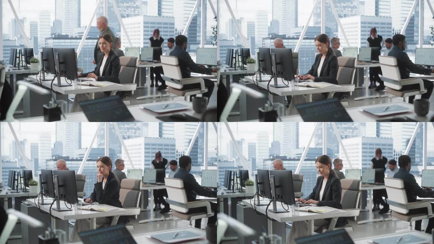 专注的女性数据分析师在明亮和多样化的公司办公室的台式电脑上打字，拥有大都市的窗口视图。与同事一起在咨