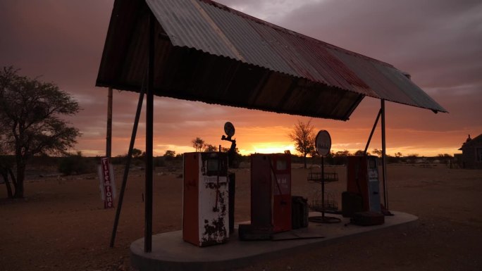 夕阳下废弃的老加油站。沙漠里生锈的坏了的关闭的气泵