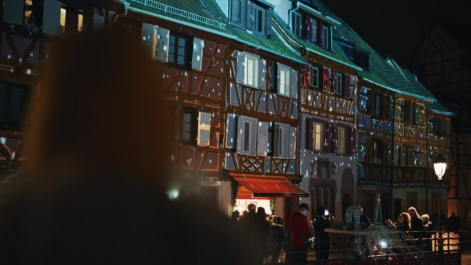 人们在科尔马欣赏传统的半木结构房屋，这些房屋被五颜六色的灯光照亮
