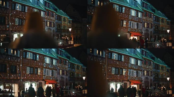 人们在科尔马欣赏传统的半木结构房屋，这些房屋被五颜六色的灯光照亮