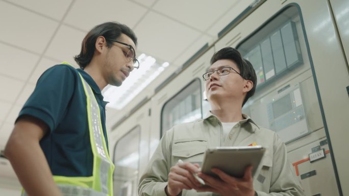 不同的亚洲工程师在电气工厂合作。