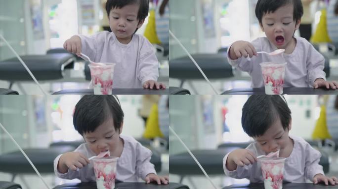 快乐的亚洲男孩在商场吃冰淇淋玩气球。
