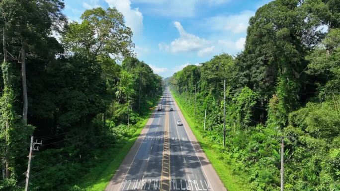 道路的空中无人机穿过泰国攀加省的森林，空中无人机镜头与电影般缓慢的全景相机运动穿过道路。