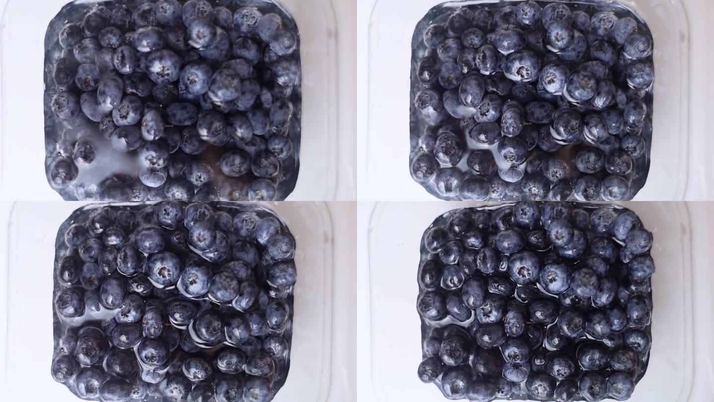 洗蓝莓。野生蓝莓的特写，慢慢地被水覆盖，慢慢地被冲走。厨房，水槽，水龙头。食用前的水果加工