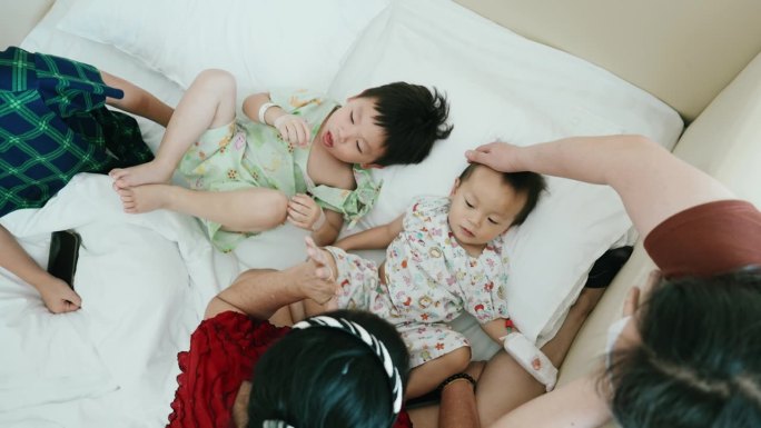 一个亚洲家庭在医学检查室等待孩子的儿科医生时给她的儿子们玩耍。健康的生活方式。甲型流感病毒。