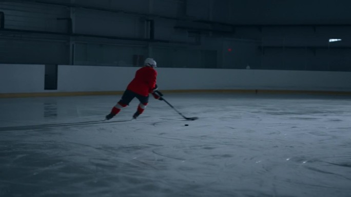 动感十足的视频，一名身穿红色球衣的冰球运动员在冰场上努力训练，展示了他令人难以置信的技术，并打进了一