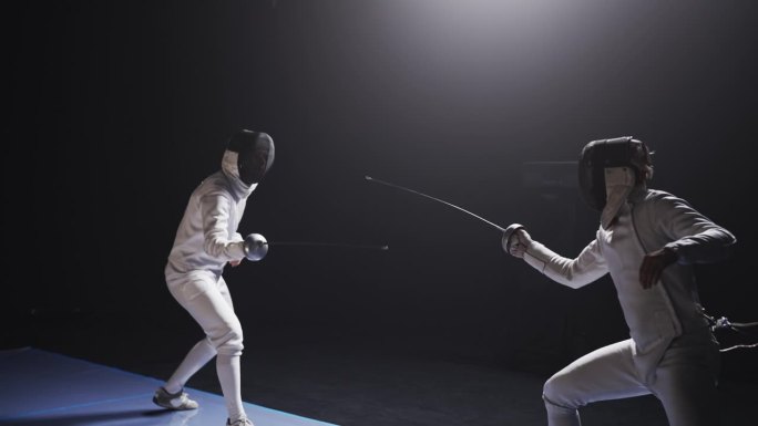 后视图两名职业击剑运动员在比赛中全副防护装备碰撞花剑。直接打胃