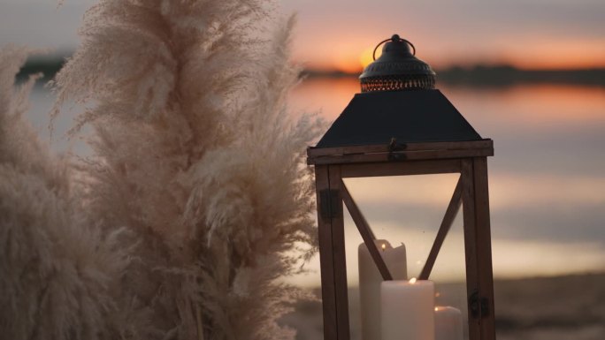 浪漫的复古装饰和蜡烛在沙滩上日落，婚礼或约会在湖岸