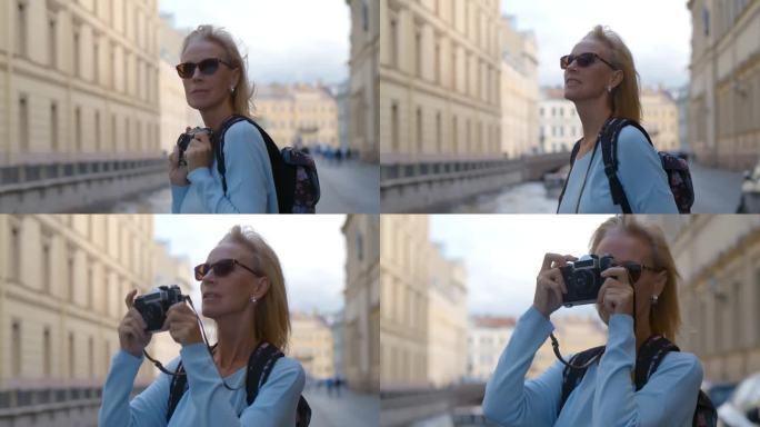 戴着墨镜的成熟女子用复古相机拍摄旧城。