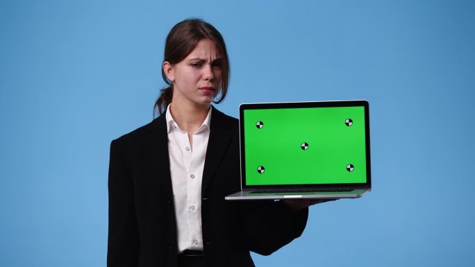 一个女孩用色度键笔记本电脑思考蓝色背景上的东西的4k视频。