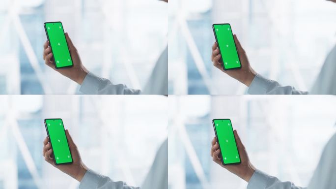匿名商人拿着绿屏模拟显示屏的智能手机，站在现代办公室里。视频模板的数字演示，业务内容创建，企业通信