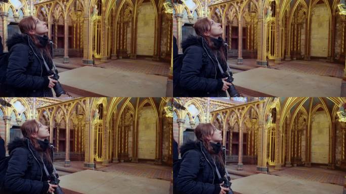 侧视图，年轻的西班牙裔妇女穿着温暖的夹克，用专业相机拍摄雄伟的哥特式教堂圣礼拜堂内部，法国巴黎