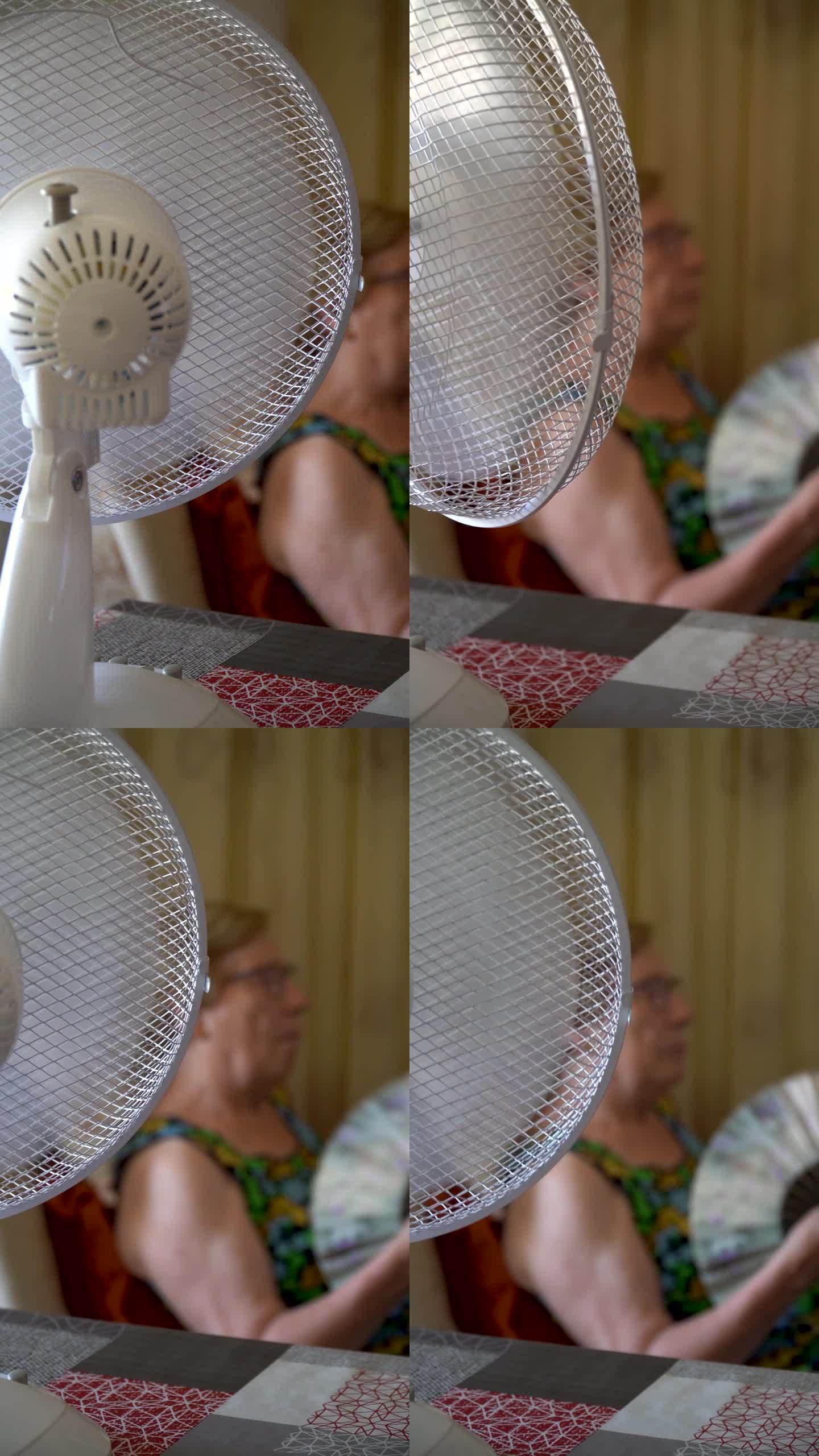 电风扇为一位年长的妇女降温，背景是手扇