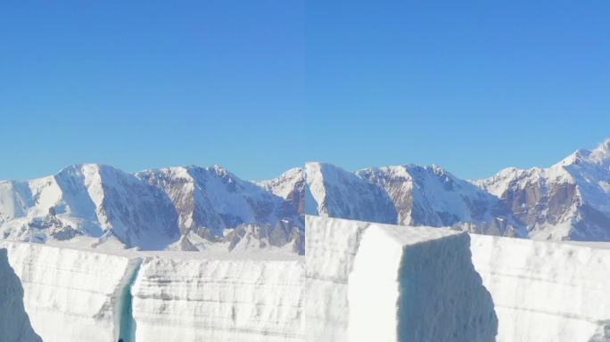 垂直镜头巨大的冰山和浮冰的背景雪山。