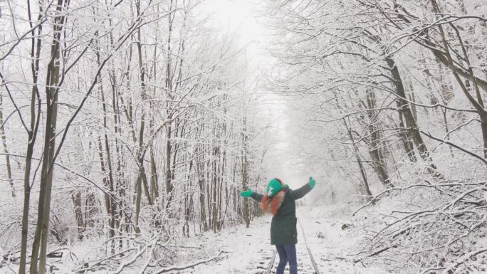 白雪覆盖的树木为沿着铁轨行走的女人创造了神话般的背景，给人以快乐和幸福。在冬天，享受新年和圣诞假期的