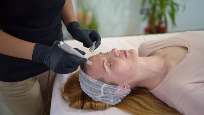 美容师在年轻女性病人脸上进行皮肤护理