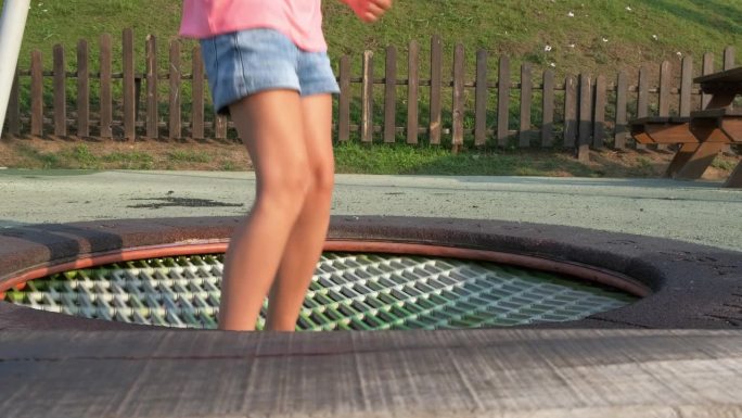公园里小孩在蹦床上蹦蹦跳跳。