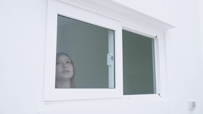 一位亚洲女士在早晨打开窗户呼吸新鲜空气。