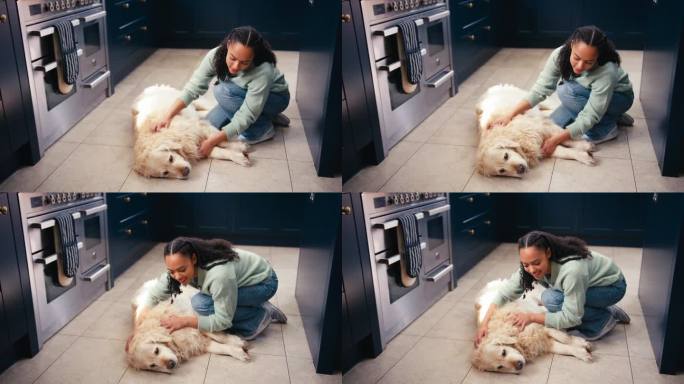 十几岁的女孩在家里的厨房抚摸着躺在地板上的宠物金毛猎犬
