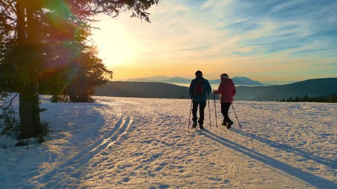 两个年长的徒步旅行者在雪地里走在乡下的某个地方。