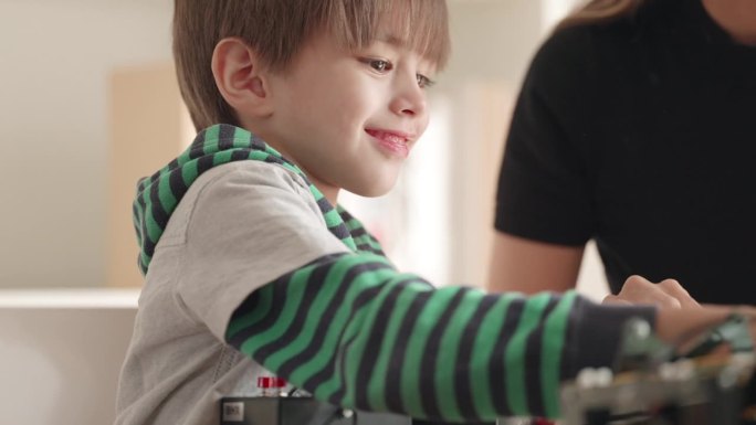 聪明的孩子男孩玩机器人玩具使用电线遥控玩干机器人玩具在家里。提高工程技能和想象力的活动。教育的创新和