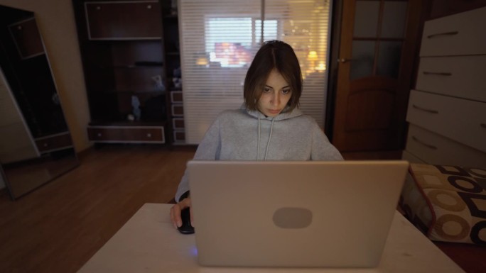 年轻专注的女人在家办公室用笔记本电脑工作。自由职业者，远程工作，在家工作。平面设计师，图像修图师在工