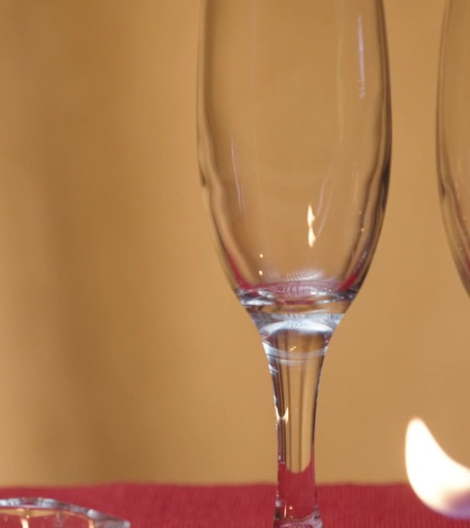 两个空香槟酒杯，放在红桌布上。我点了三支蜡烛。做一顿浪漫的晚餐。垂直视频社交媒体