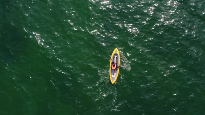 无人机拍摄的一名男子在开阔的海面上划着独木舟的俯视图。