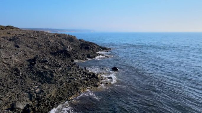 无人机飞离悬崖波浪在深蓝的天空和大海4K HDR