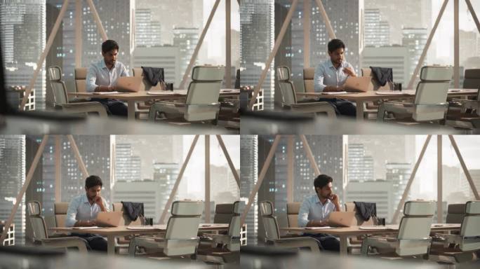 一位年轻的印度客户经理在现代公司办公室里用笔记本电脑工作的肖像。处理财务报告，为公司准备增长计划