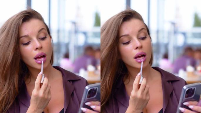 垂直视频显示，一名女子在路边餐馆的手机摄像头前涂口红。