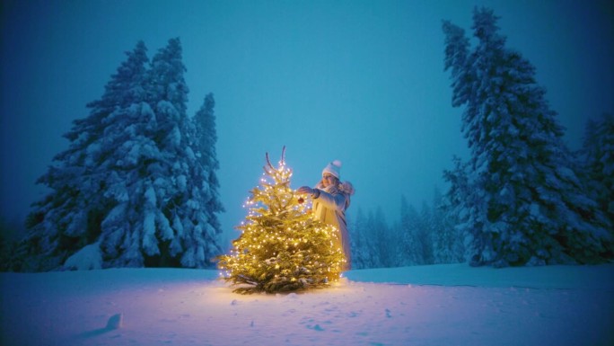白雪覆盖的林间空地上，一名妇女把装饰品挂在圣诞树上