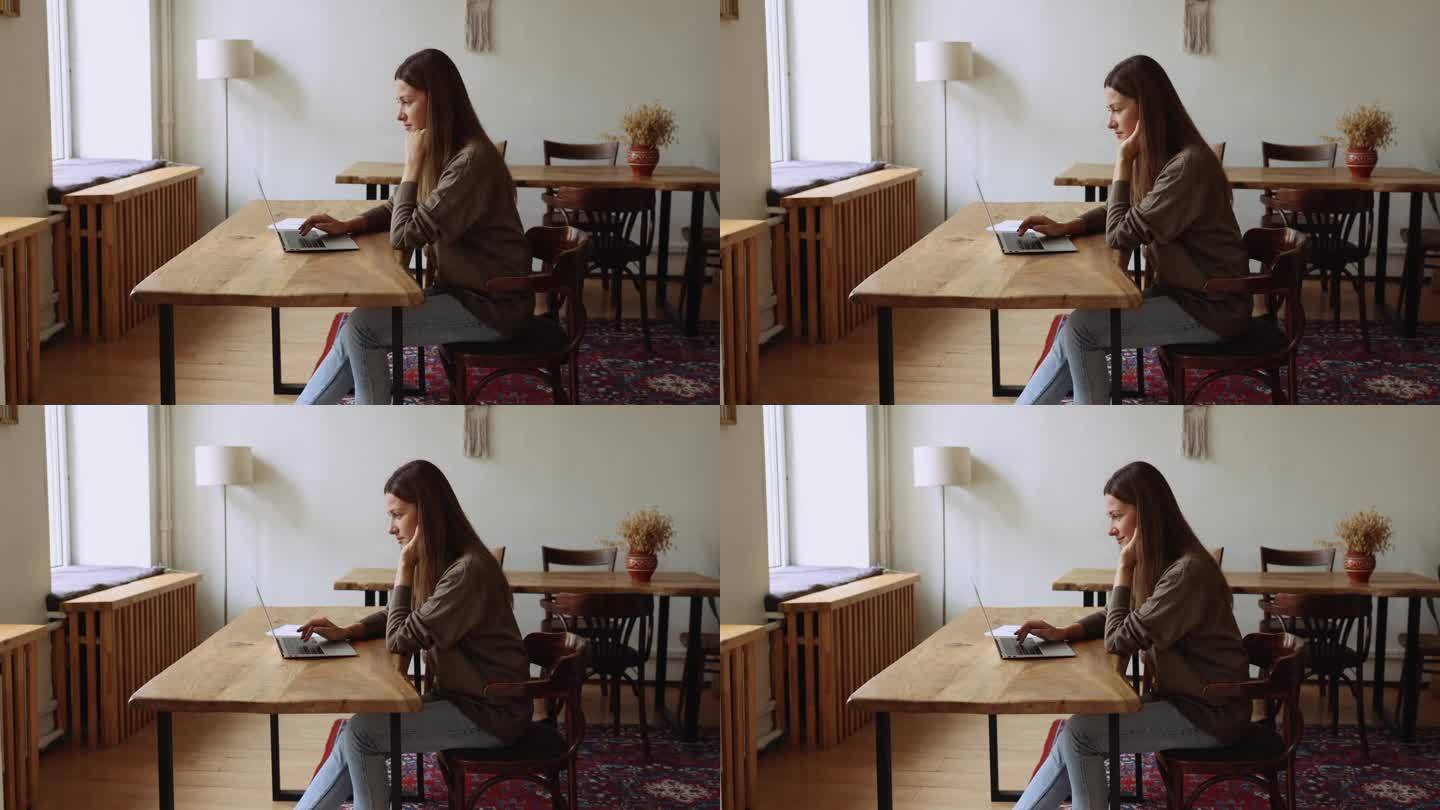有魅力有思想的女人坐在办公桌前用笔记本电脑远程工作