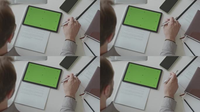 男子做文书工作和使用绿色屏幕的数字平板电脑