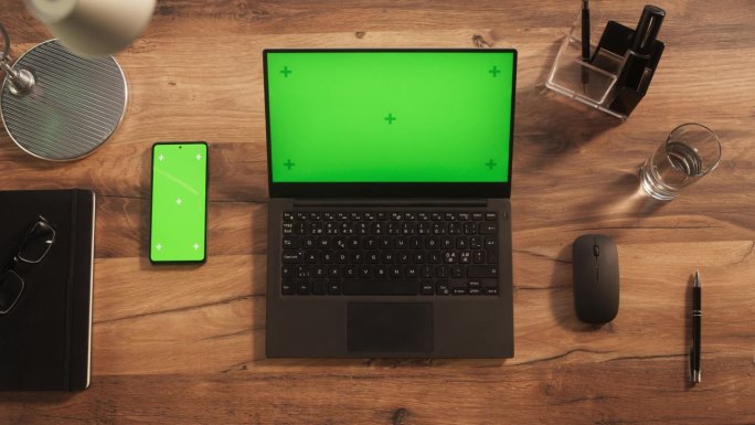 一台笔记本电脑的俯视图与模拟绿屏站在办公桌旁边的智能手机与模板Chromakey显示与运动跟踪占位符