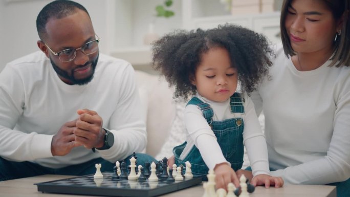 女儿和家人下棋，一种智能游戏，多民族家庭在家里下棋，爸爸妈妈和孩子一起做活动
