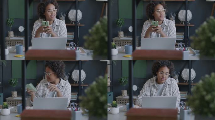 自由职业者的肖像，非洲裔美国人使用智能手机短信，然后在办公桌上用笔记本电脑工作