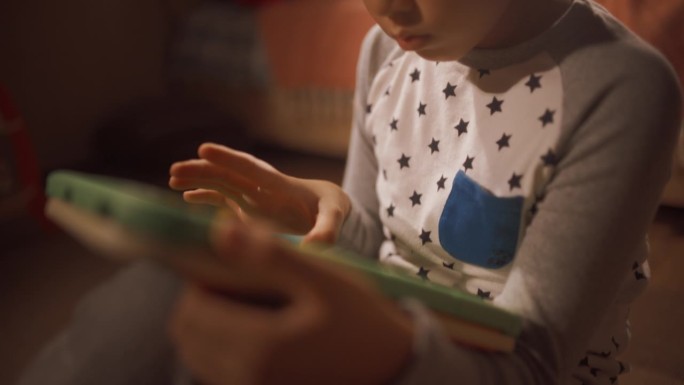 一个可爱的韩国学龄前男孩在他的房间里学习使用平板电脑的特写。集中的亚洲儿童在家里用电脑玩教育游戏