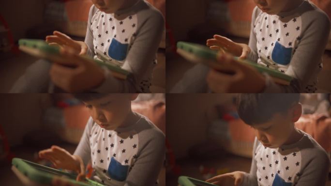 一个可爱的韩国学龄前男孩在他的房间里学习使用平板电脑的特写。集中的亚洲儿童在家里用电脑玩教育游戏