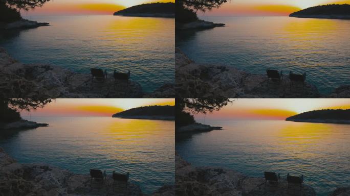 日落时分，在田园诗般的大海前的岩石上的甲板椅子