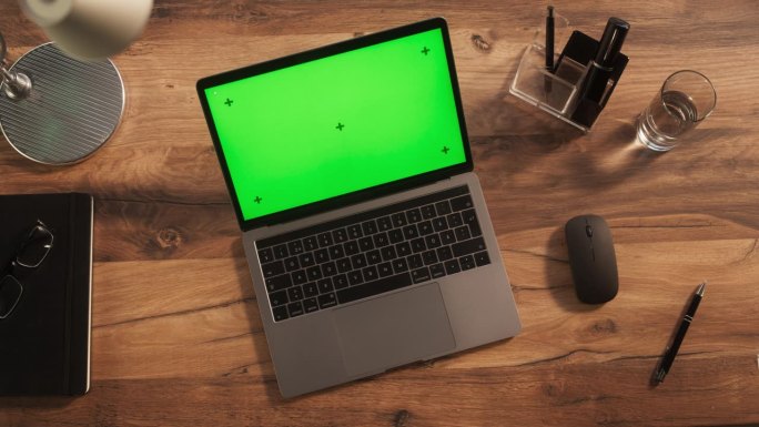 笔记本电脑的俯视图，模拟绿屏Chromakey显示器与运动跟踪器站在木制办公桌旁边的无线鼠标，黑色钢
