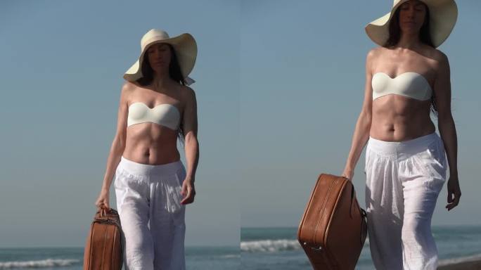 一个成熟的女人带着棕色的手提箱走在太平洋的黑色沙滩上