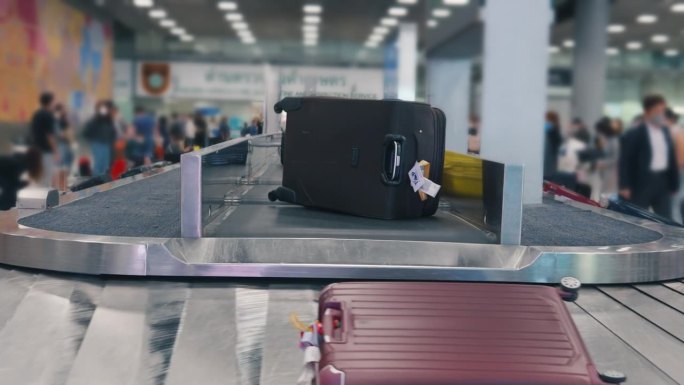 行李袋在传送带上运输，在机场航站楼的传送带上，人们在高峰时间等候