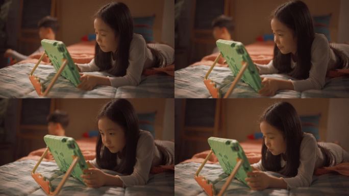 聪明的韩国女孩在孩子的卧室里用平板电脑玩益智视频游戏。快乐的姐姐和哥哥喜欢在家里度过创造性的时间