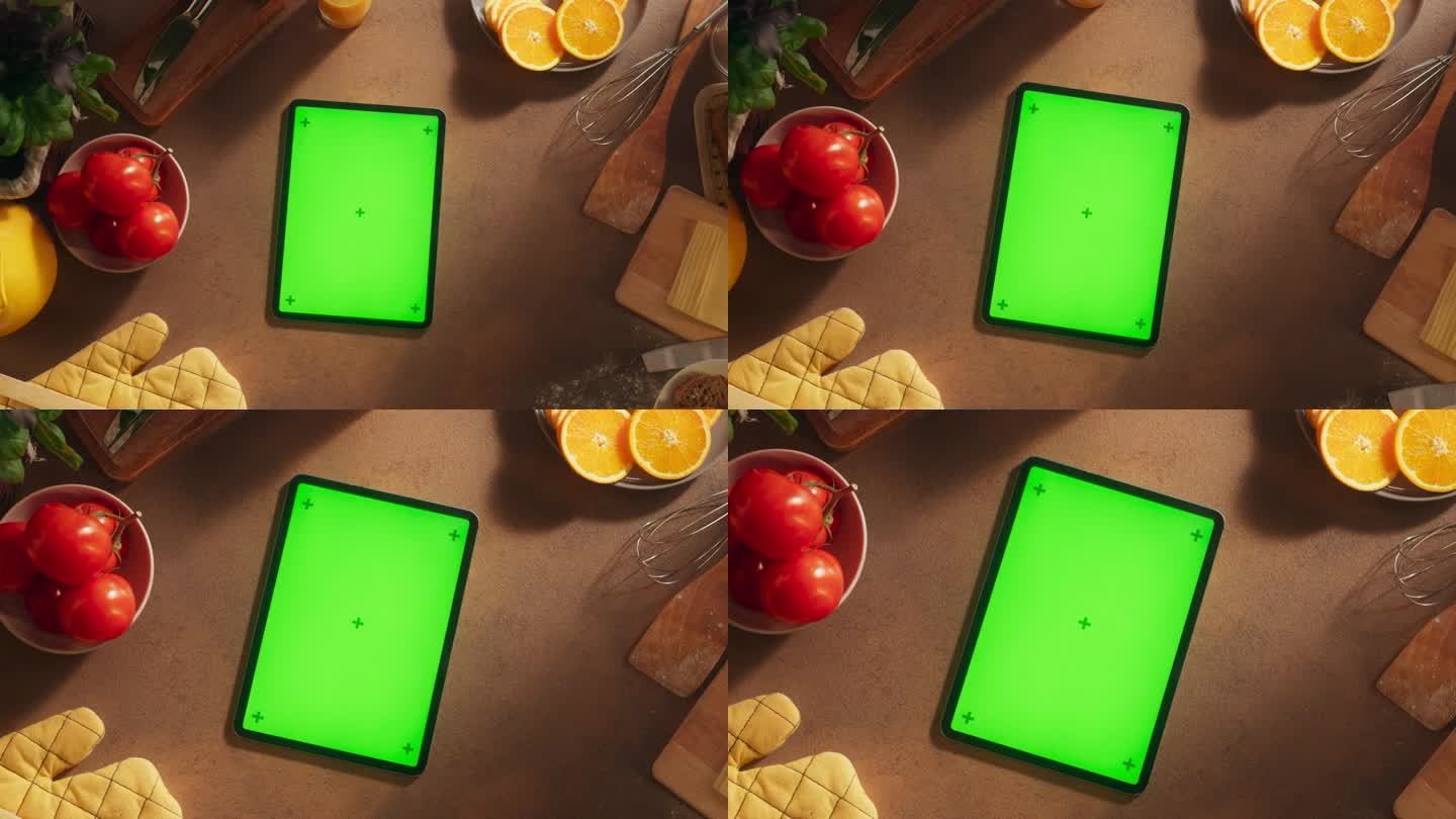 从上到下放大的平板电脑与模拟绿色屏幕显示视图。数字设备模板垂直躺在厨房的桌子上，周围是健康的食物和新