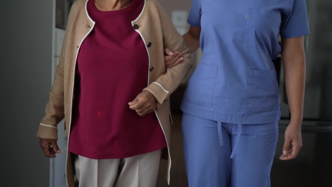 家庭护工帮助老年妇女在家里走路