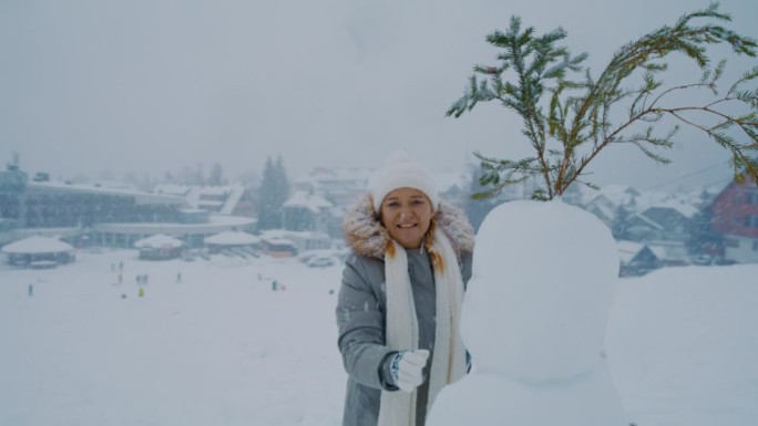 一名妇女在朱利安阿尔卑斯山小镇的斜坡上堆雪人